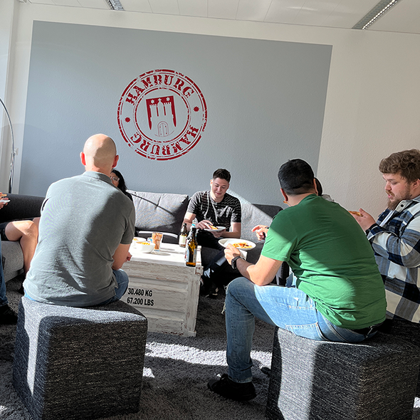 Foto: Mitarbeiter sitzen im Pausenraum zusammen und essen