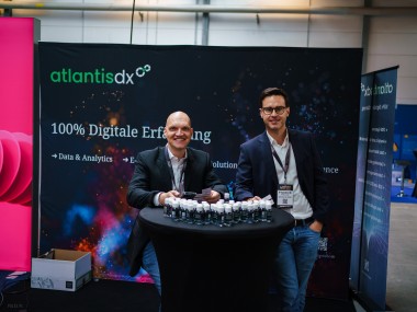 atlantis dx - E-Commerce Berlin Expo 2022 Foto: Denis Rathig und Radek Paluszak stehen an einem Messestand von atlantis dx