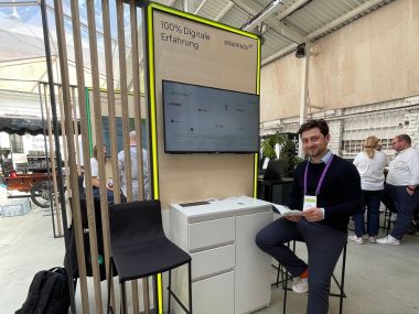 atlantis dx - Zendesk Showcase 2025 Mann sitzt lächelnd an einem Stand mit digitalem Bildschirm