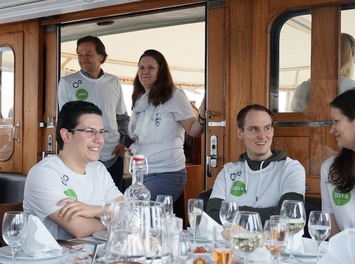 atlantis dx - 25 Jahre Firmenjubiläum Foto: Menschen in weißen T-Shirts sitzen an einem Tisch mit Essen und Getränken