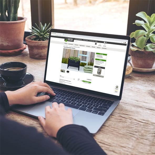 Mein Gartenversand - conception and realization of the Magento online store Laptop with open online store on a wooden writing desk with green plants on the table