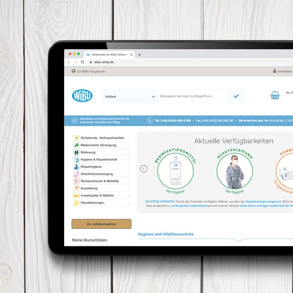 WIBU Group - Realization of two consecutive stores based on Magento Close-up of tablet with open online store on white wooden background